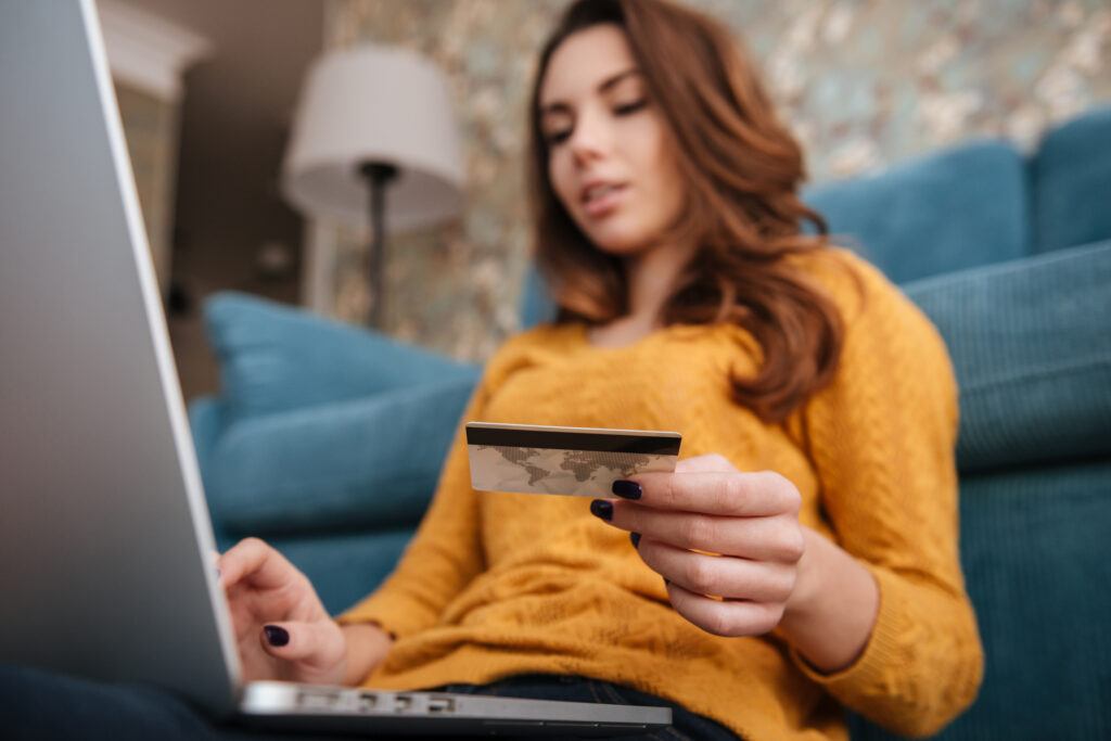 woman holding credit card and shopping on laptop