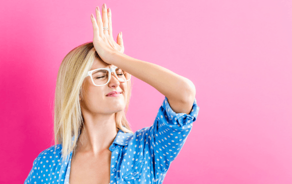 Blonde woman in a blue shirt pressing her hand against her head