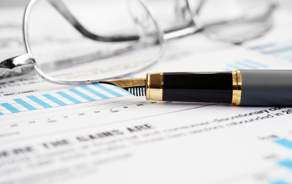 Eyeglasses and a black and gold fountain pen on a document with printed text and blue charts.