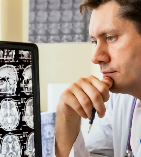 A medical professional in a white lab coat with a stethoscope, thoughtfully examining MRI brain scans on a lightbox.