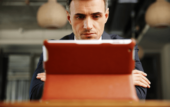 Man in a suit watching a video on a tablet