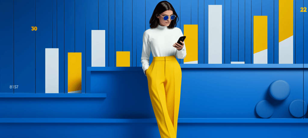 Woman in sunglasses, a white shirt, and yellow pants leaning against a wall while she looks at her phone