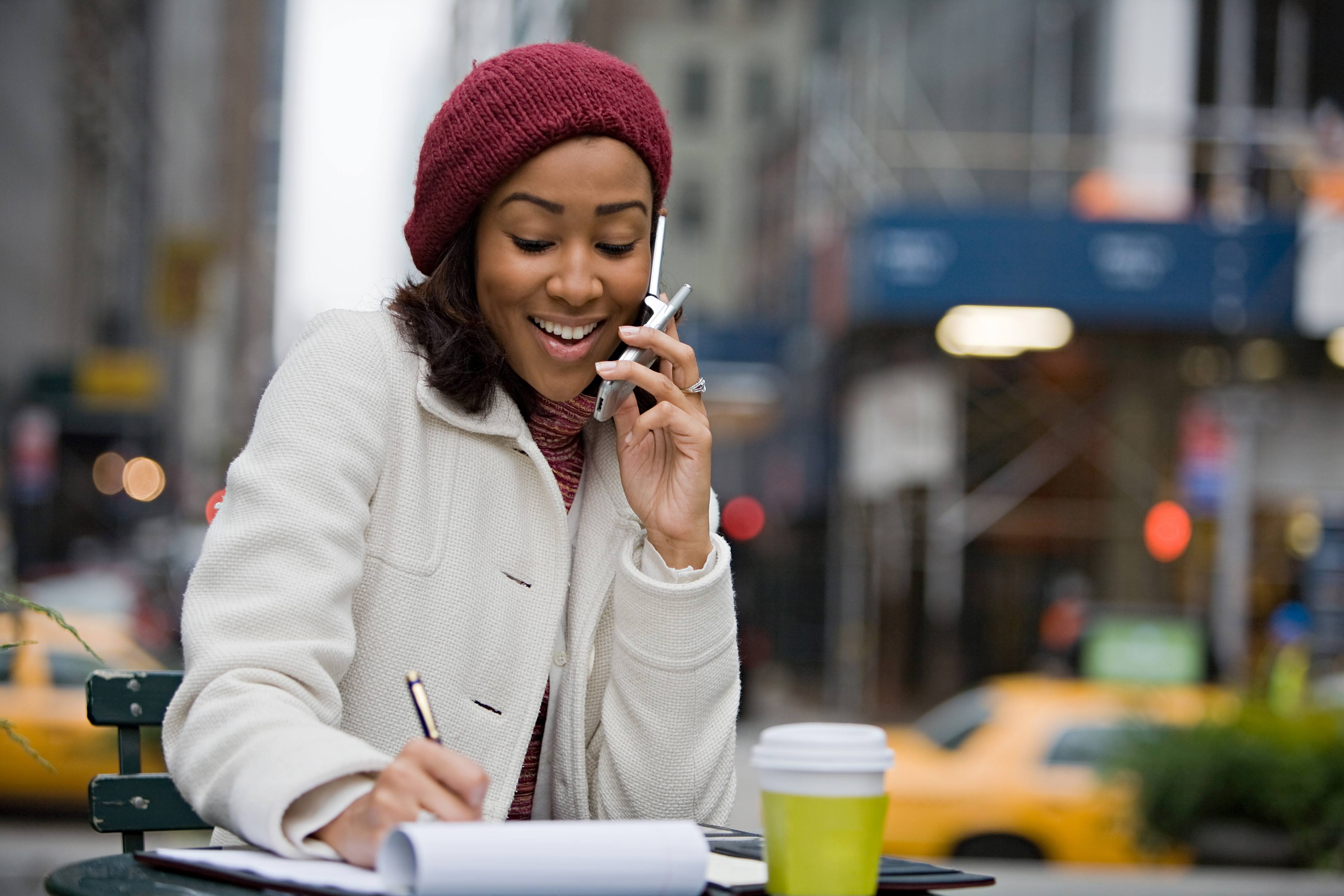 A business woman talking on her cell phone while seated outdoors in the city.