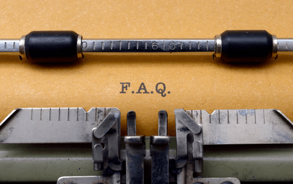 Close-up of a vintage typewriter with the text 'F.A.Q.' typed on a yellowish paper.