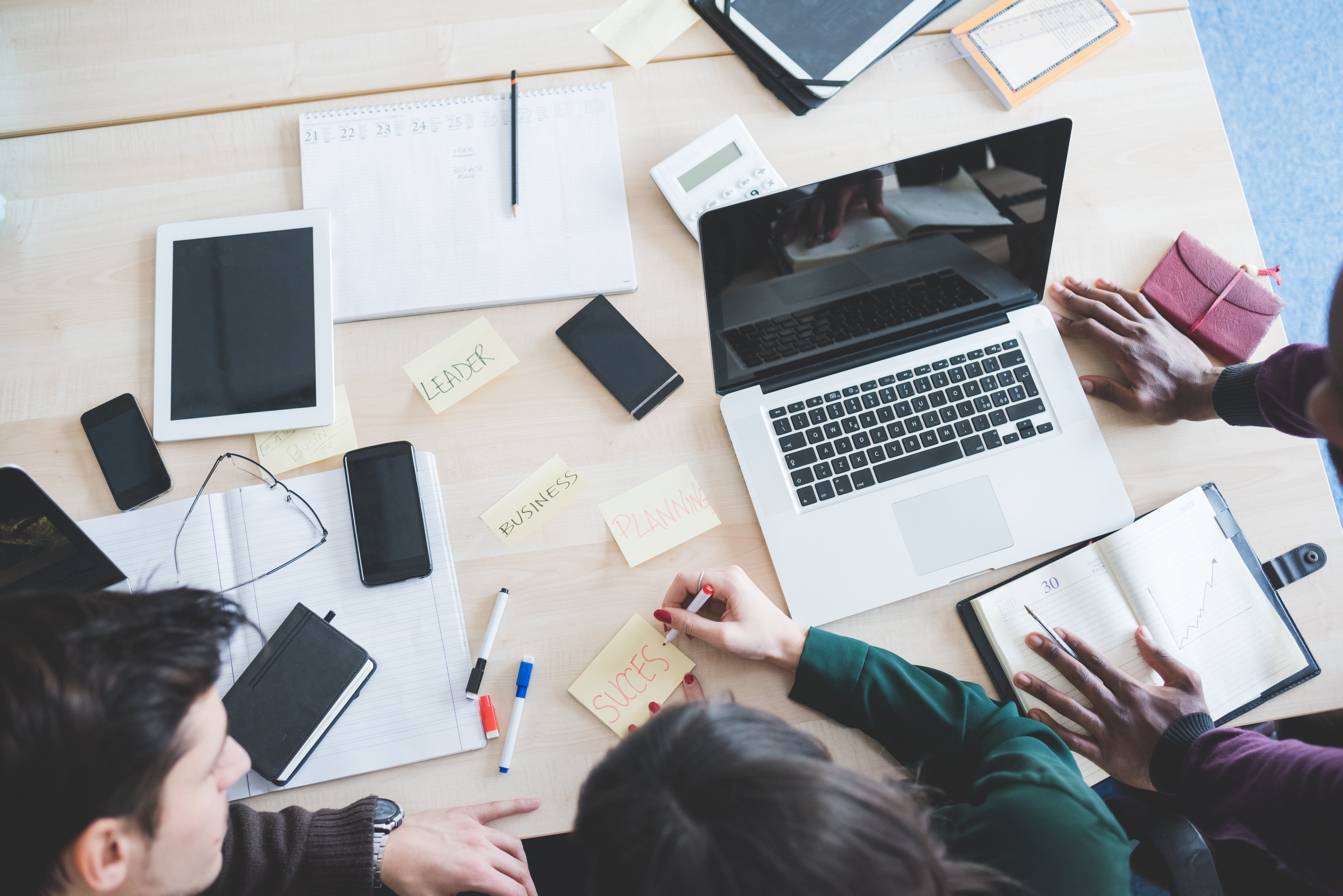 Top view of working desk with three multiethnic people working - business, teamwork, brainstorming concept