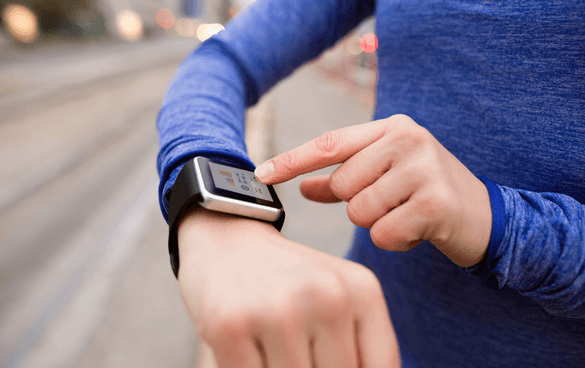 A person checking a smartwatch on their wrist while standing outdoors.