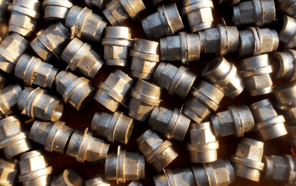 A collection of shiny metallic bearings or bushings with grooves, scattered across a surface.