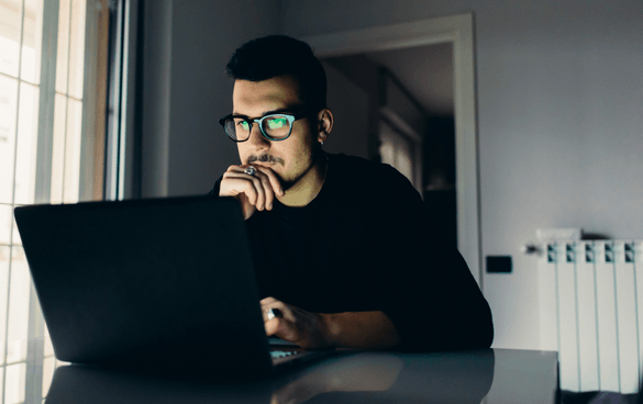 Young man with glasses staring at a laptop