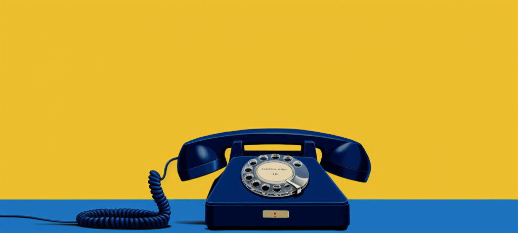 A dark blue rotary dial telephone with a silver dial and black numbers on a split yellow and blue background.