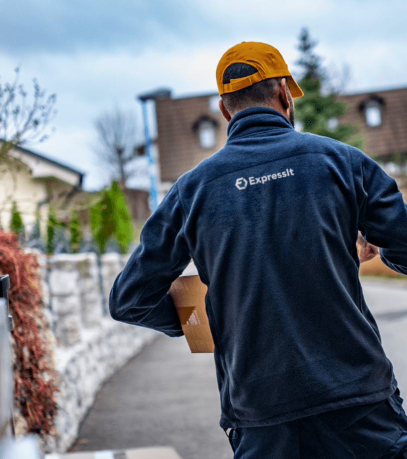 Delivery worker from Expressit walking with a package in a residential area.