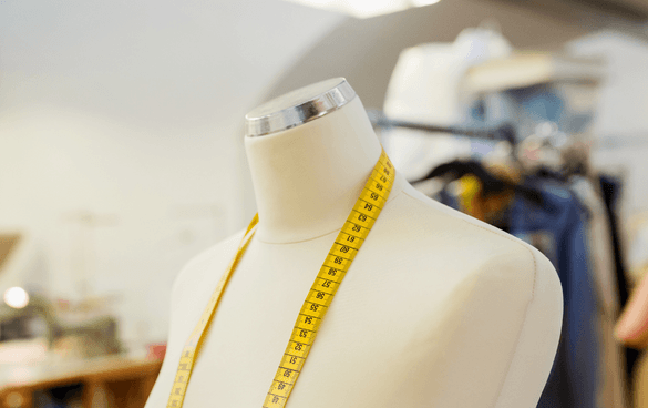 A mannequin torso with a measuring tape around its neck in a fashion design studio.