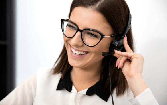 Smiling woman with glasses wearing a headset with a microphone, likely working in a customer service role.