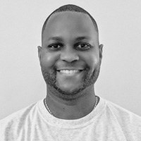 Portrait of a smiling man with a short haircut, wearing a white t-shirt.