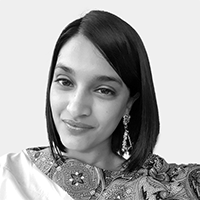 Portrait of a smiling woman with shoulder-length straight hair, wearing earrings and embroidered clothing.