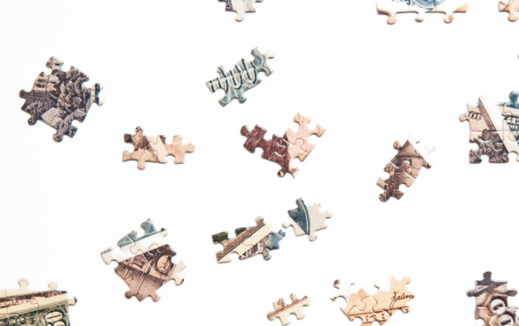 Scattered jigsaw puzzle pieces with parts of an image on a white background.