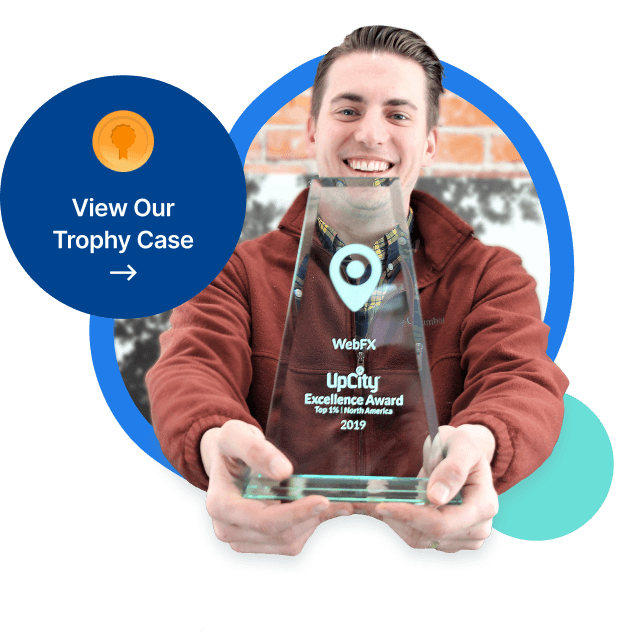 A smiling person holding a clear glass trophy with the text 'WebFX UpCity Excellence Award Top 1% North America 2019'.