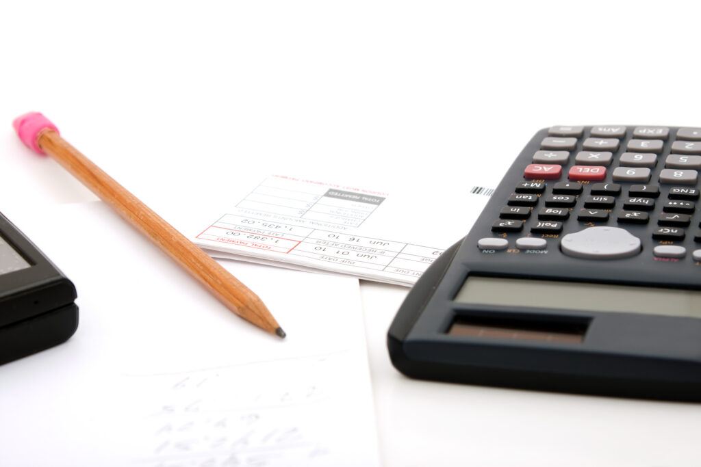 Adding up the monthly revenue for business accounting. A calculator pencil and paperwork. isolated over white.