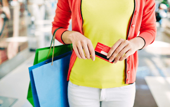 Woman with two shopping bags on her arms and a credit card in her hand shopping in a mall