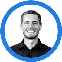 A smiling man with short hair and a beard, wearing a dark shirt, encircled by a blue outline against a white background.