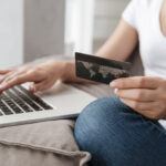 Closeup of woman with laptop and credit card doing online shopping at home