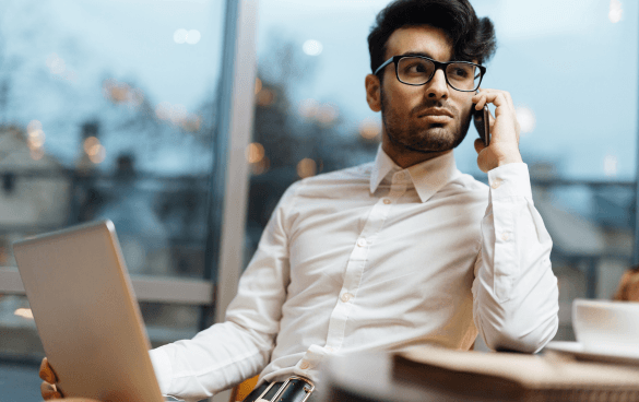 Man dressed in white button up shirt with glasses talking on a cell phone