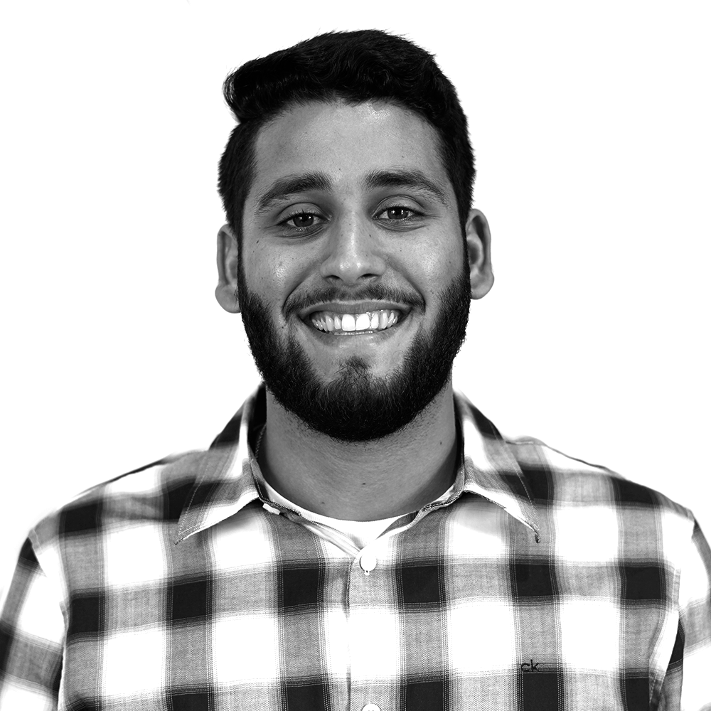 A smiling man with a beard wearing a checkered shirt.