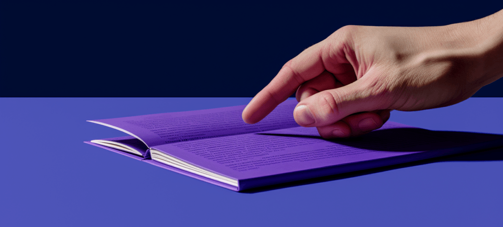 A hand pointing to a line of text on a purple page of an open book, set against a deep blue background.