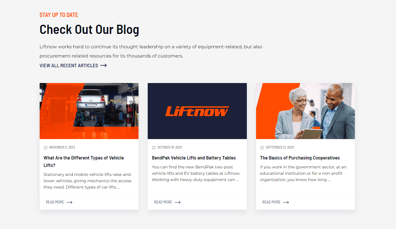 Webpage section with blog posts on vehicle lifts and purchasing cooperatives, including images of a car on a lift, the LiftNow logo, and two people reviewing a document.