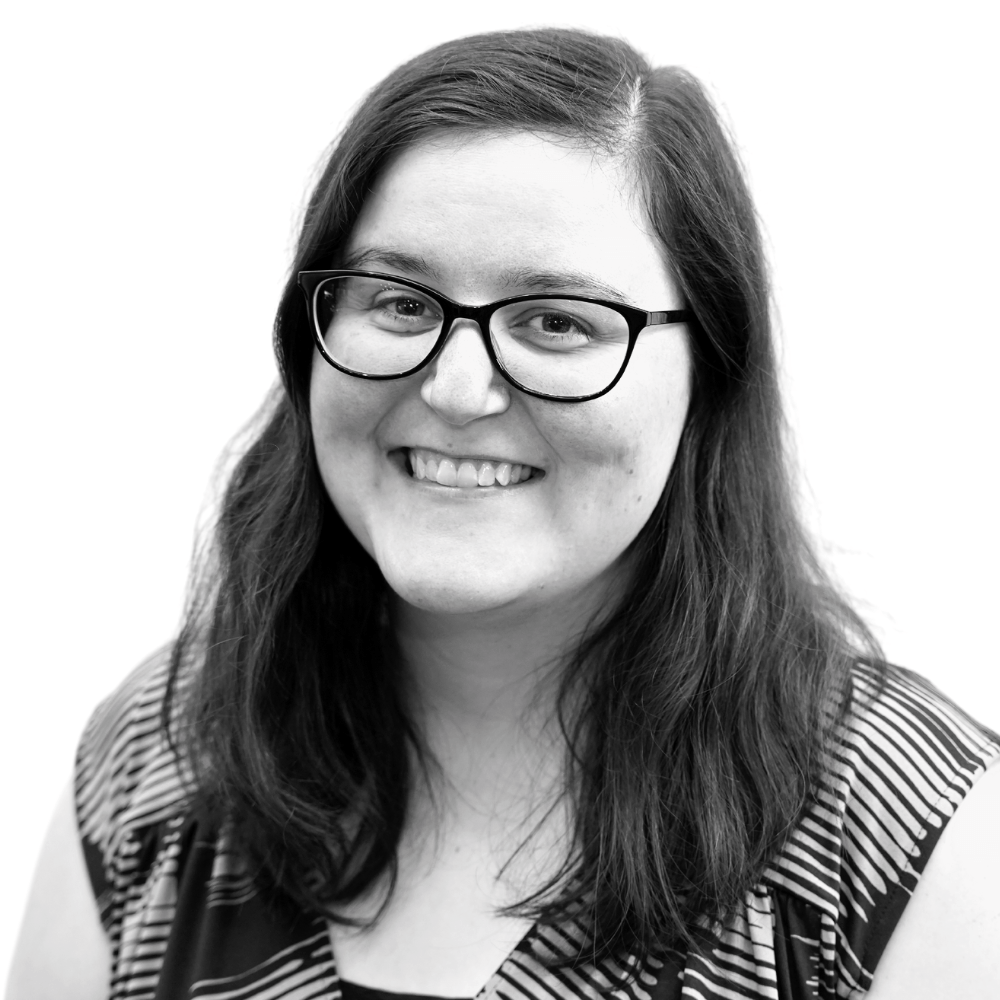 Black and white portrait of a smiling woman with glasses.