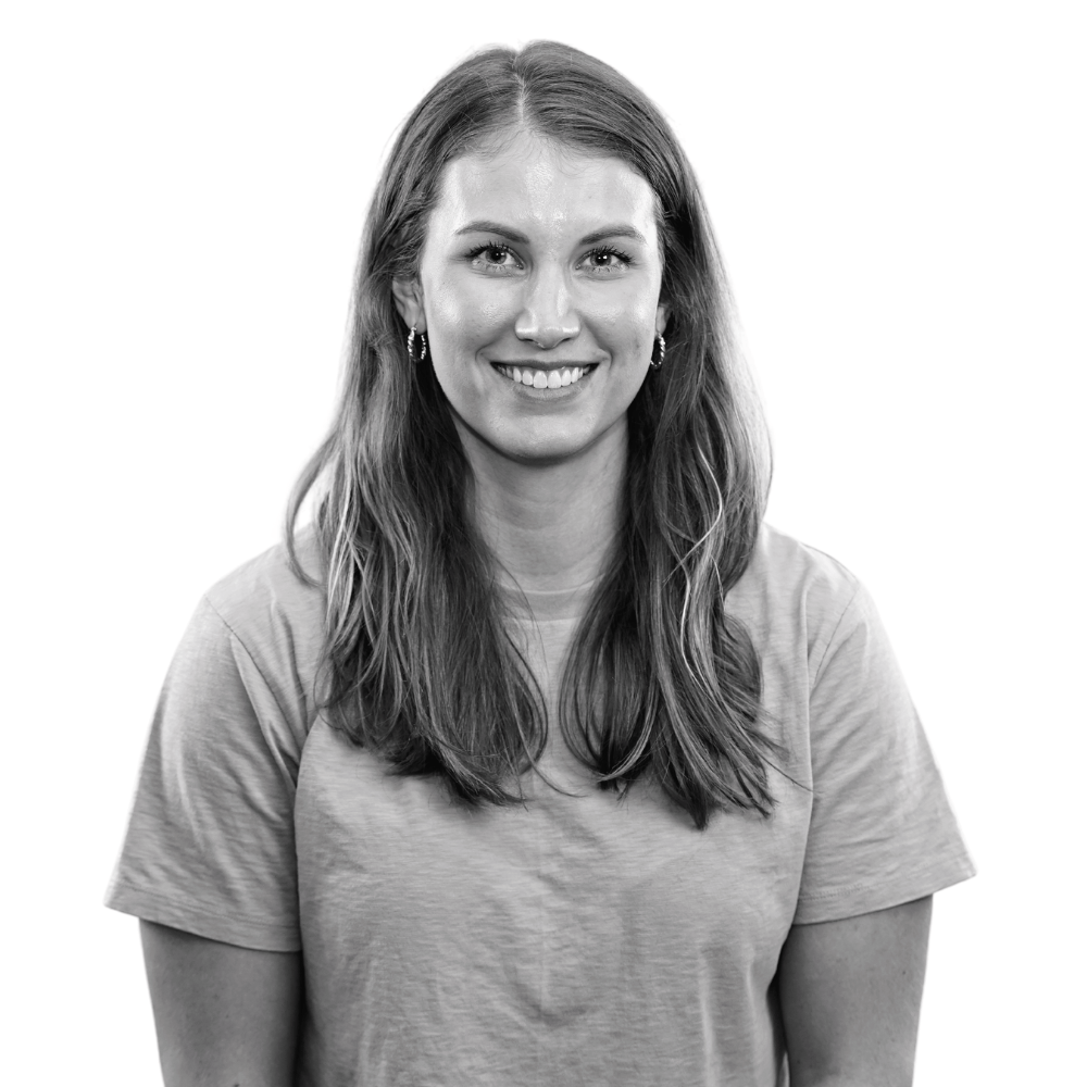 Black and white portrait of a smiling woman with long hair wearing a t-shirt and earrings.