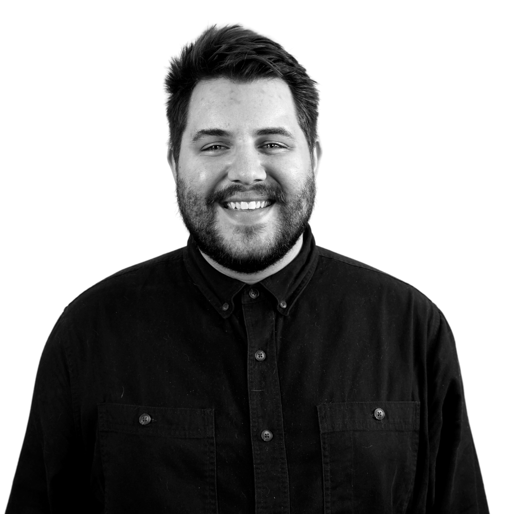 A smiling man with short dark hair and a beard, wearing a black button-up shirt.