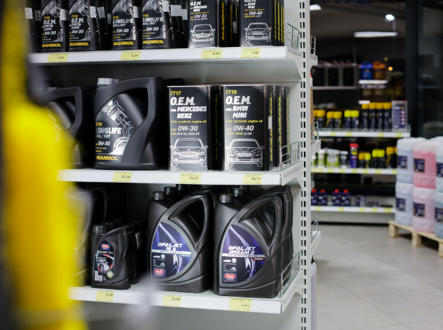 Shelf in a store displaying motor oil containers with labels indicating different viscosities and specifications for Mercedes and BMW vehicles.