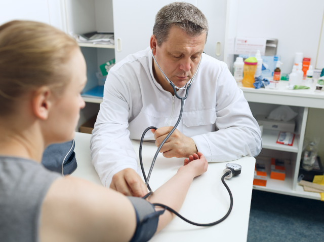 A healthcare professional checking a patient's blood pressure in a clinical setting.