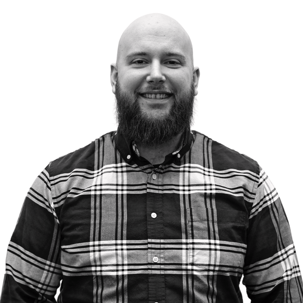 Smiling bald man with a full beard wearing a plaid shirt.