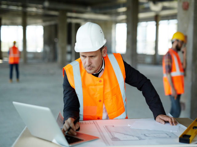 Man in construction uniform looking at laptop