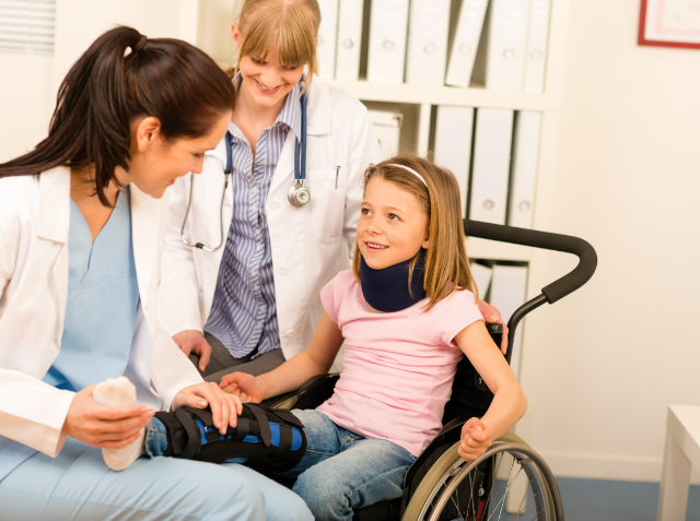 A healthcare professional adjusts an arm brace on a smiling young girl in a wheelchair, while another healthcare professional observes, in a clinical office setting.