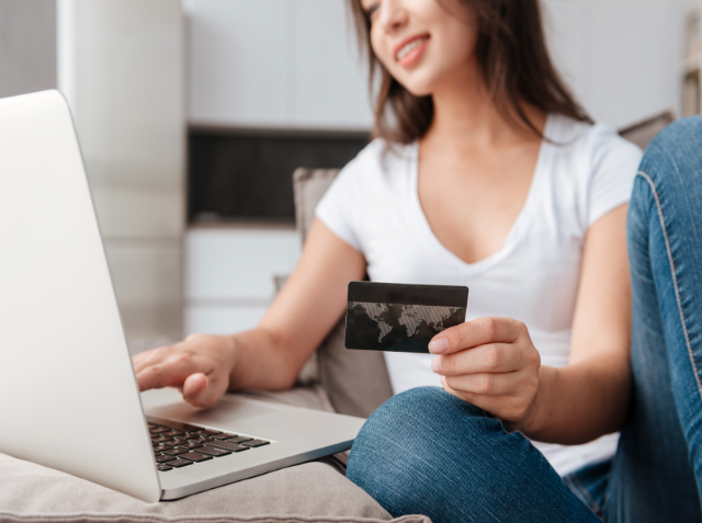 A woman at a laptop holding a credit card