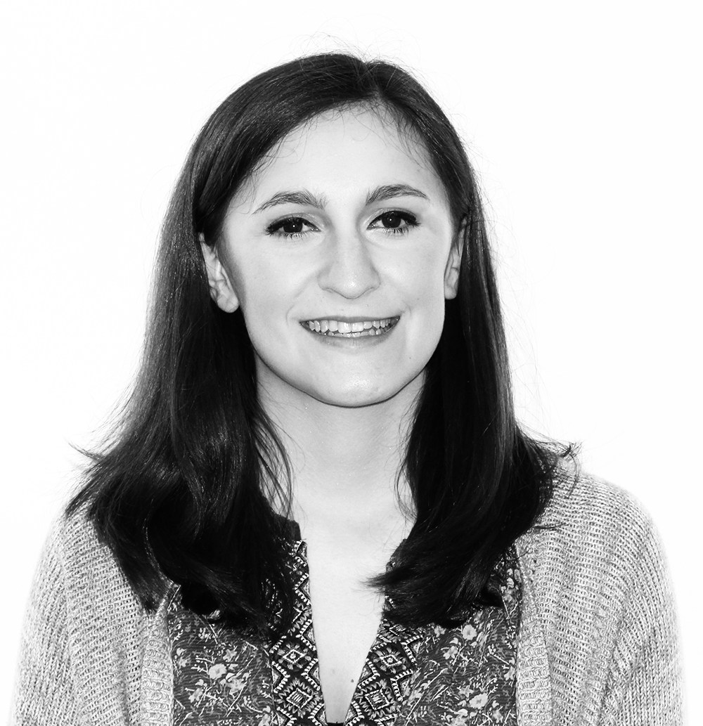 Black and white portrait of a smiling young woman with shoulder-length straight hair wearing a patterned top.