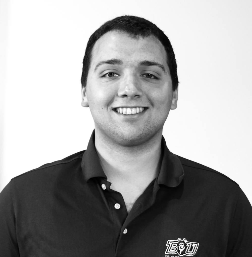 A smiling young man wearing a dark polo shirt with a BYU logo on the right chest.