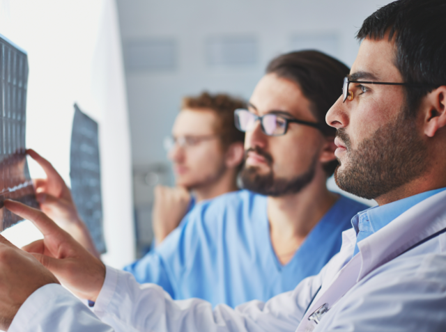 Three medical professionals analyzing an X-ray film together.