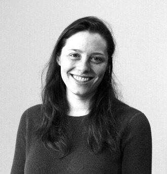 Black and white portrait of a smiling woman with long hair wearing a sweater.