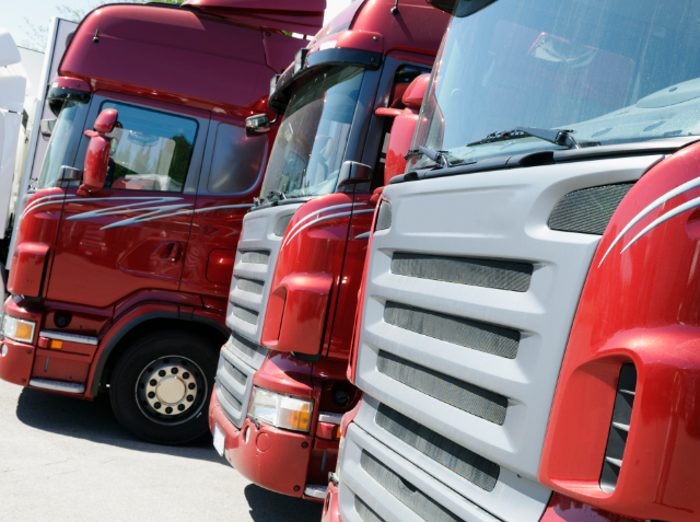 Close-up of two parked semi-trucks, one red with a classic design and the other white with a modern design.