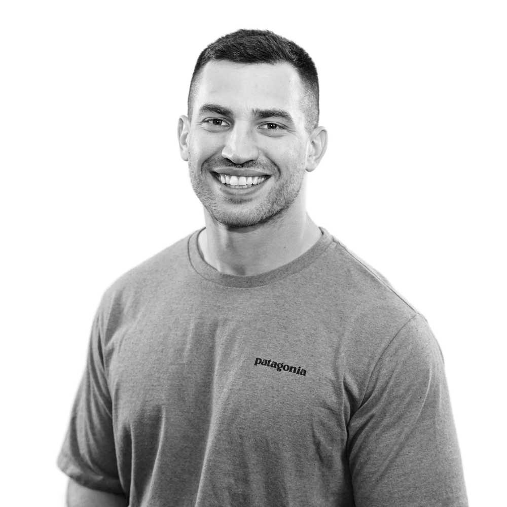 Smiling man with short hair wearing a Patagonia t-shirt in a black and white portrait.