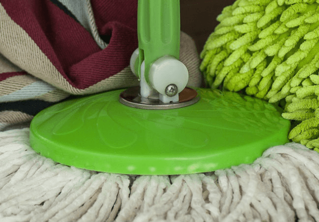 Green mop sitting among cleaning supplies