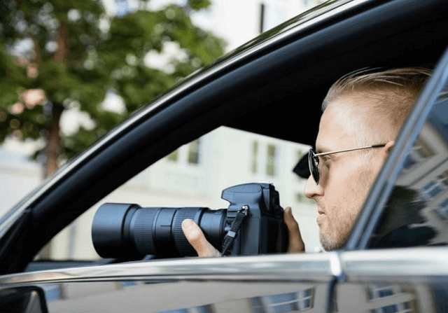 Private investigator in car with camera