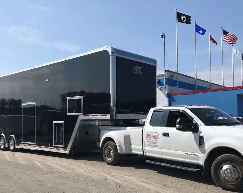 White truck with a black trailer hitched to the back