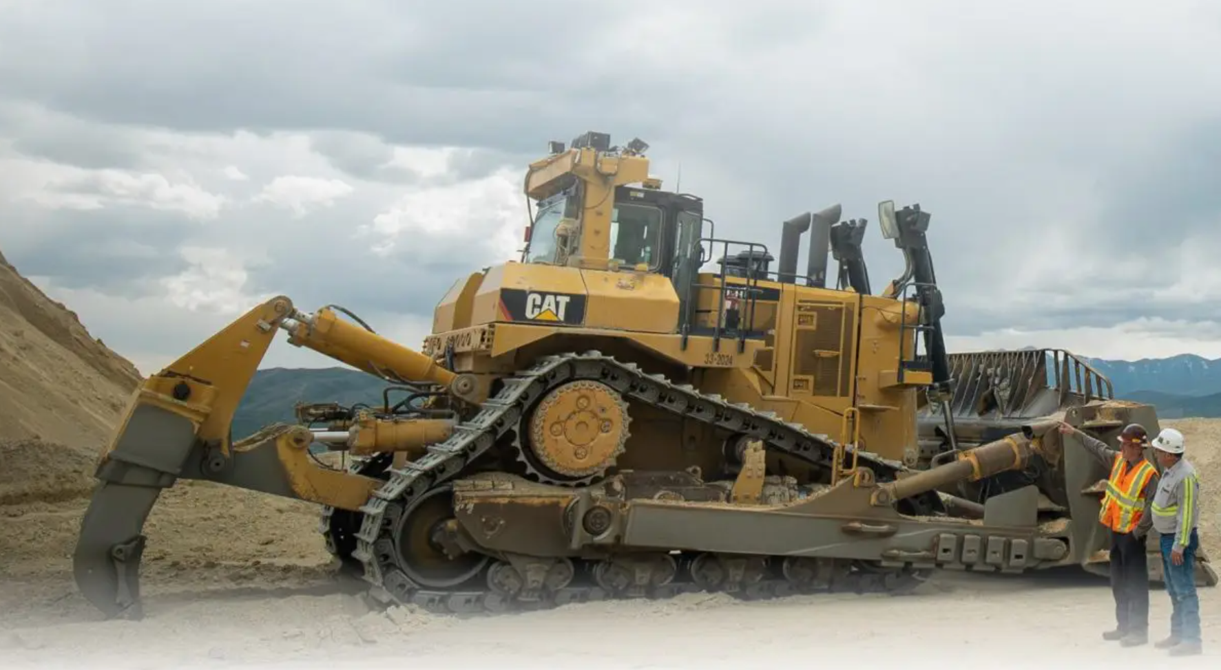 Heavy equipment machine working next to two construction workers planning