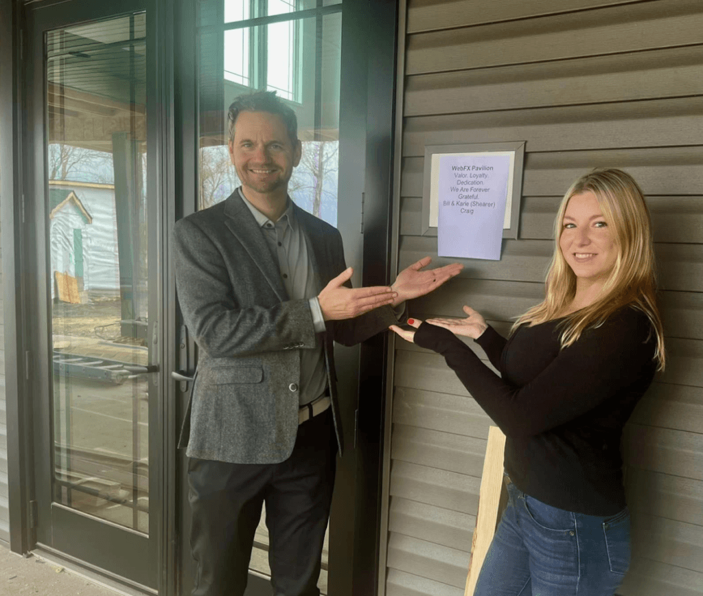 Bill and Karie gesturing towards a paper indicating the WebFX pavilion 