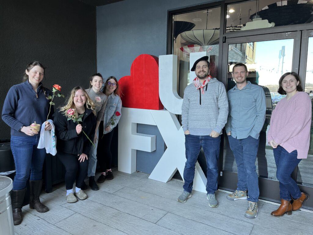 WebFX marketing team standing around the heart U FX sign