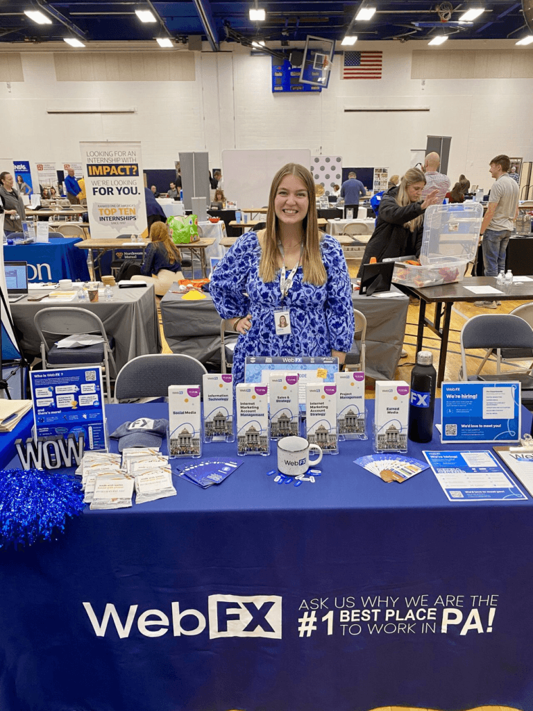 Julie standing behind a WebFX table at a career fair